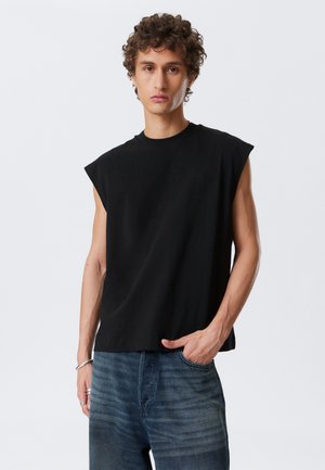Black sleeveless shirt with a round neck, made of soft fabric. Features a relaxed fit and a smooth texture. Worn with blue denim jeans.