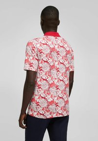 Korte mouw shirt met een wit en rood tropisch bladpatroon, voorzien van een effen rode kraag en een lichte stofstructuur.