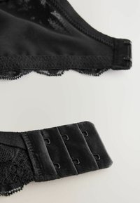 Zwarte kanten bh met een gladde stofafwerking en geschulpte afwerking. Voorzien van verstelbare schouderbanden en een haak-en-oogsluiting op de band.