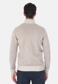 Maglione beige con colletto e polsini a coste, motivo a maglia testurizzato e silhouette aderente. Il design ha un aspetto morbido e minimalista.