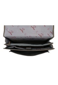 Bolso de mano gris con un interior impermeable que cuenta con múltiples compartimentos, un bolsillo con cremallera y un patrón de vaca de dibujos animados que se repite en el forro de tela.
