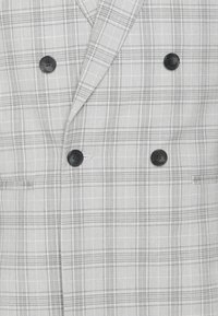 Blazer doppiopetto grigio a quadri caratterizzato da bottoni neri, revers a snotch e due tasche frontali, con un motivo di tessuto testurizzato.