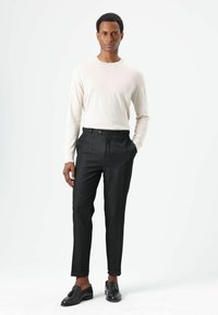 Hellfarbiger, figurbetonter Pullover; dunkle, maßgeschneiderte Hose mit leichtem Glanz; schwarze Loafers; glatte Textur; minimalistisches Design.
