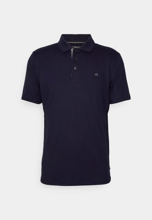 Tumesinine polo särk, mis on valmistatud puuvillasegusest kangast. Omab klassikalist kraed, kolme nupu kinnitust ja väikest brodüüri logoga rinnal.