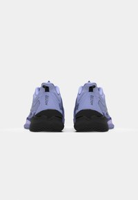 Baskets de sport violettes avec une tige texturée, semelle noire et petits accents. Elles disposent d'une languette au talon et d'une marque sur le côté.