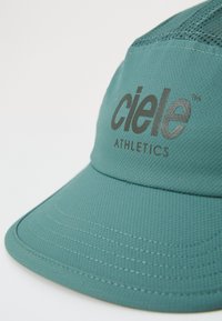 Teal athletic cap made of textured fabric, featuring a curved brim and embossed "ciele ATHLETICS" logo in dark gray.