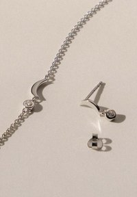 Silberner Schmuckset, bestehend aus einem Armreif mit einer Halbmondform und einem Edelstein sowie passenden Ohrringen in Halbmondform mit runden Akzenten.