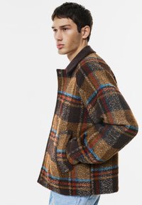 Hnedá károvaná bunda s kombináciou modrých a červených línií, s mäkkou textúrou a kordovým golierom, bočnými vreckami a voľným strihom.