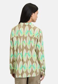 Camicia a maniche lunghe in tessuto leggero con un motivo astratto marrone, verde e crema. Include un colletto classico e polsini con bottone.