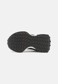 Black rubber sole of a sneaker with round grip patterns, shown against a plain white background.