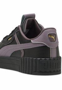 Schwarze und lavendelfarbene Sneaker aus strukturiertem Kunstleder, mit gepolstertem Kragen und dicker Gummisohle. Mit goldfarbener Logo-Akzent am Fersenbereich.