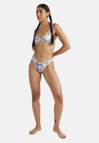 Blue bikini with white floral pattern and contrasting trim; features triangular top and high-cut bottoms; material is smooth and fitted.