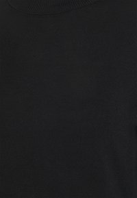 Svart ribbat stickat tyg med en närbild av en rundad halsringning på en skjorta eller tröja.