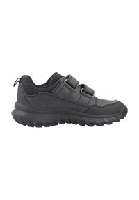 Zapatilla deportiva negra con suela gruesa y texturizada y dos correas de velcro ajustables sobre un fondo blanco.