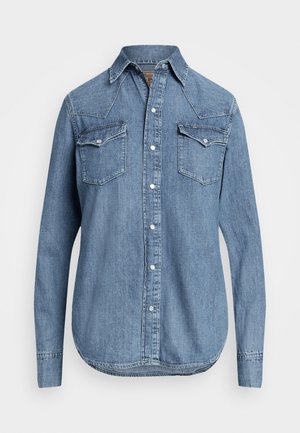 Langærmet blå denimskjorte med knapper foran og to brystlommer med knapper på hvid baggrund.