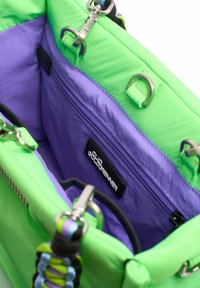 Groene nylon tas interieur met een paarse voering, een ritsvak en hardware accenten. Inclusief een geweven schouderband met meerdere kleuren.
