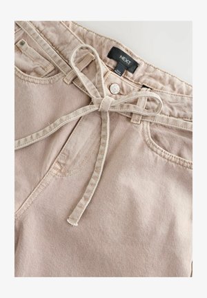 Pantaloni in cotone rosa chiaro con frontale piatto, cintura a fiocco e texture sottile. Presenta una chiusura con bottone e tasche frontali. Etichetta: NEXT.