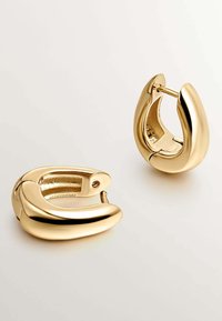 Pendientes de aro dorados con una superficie suave y brillante. Tienen una forma curva y orgánica y un cierre de bisagra para facilitar su uso.