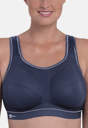Marineblauwe sportbeha van rekbare, ademende stof. Voorzien van bredere banden, gebogen naden en contrasterende stiksels voor ondersteuning en comfort.