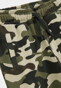 Camo-mönstrade sweatpants i nyanser av grön, beige och mörkbrun; elastisk midja med justerbar dragsko; sidofickor.