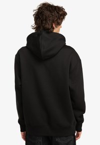 Black hoodie made of soft fabric, featuring a large hood, dropped shoulders, and ribbed cuffs. Smooth texture with no visible patterns.