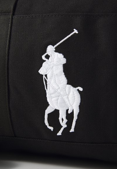 Crna torba od tkanine s istaknutim bijelim izvezenim logotipom konjanika s maljem, koji prikazuje detaljno šivanje i teksturu.