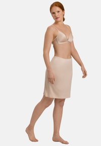 Nude slip nederdel lavet af glat stof med elastisk talje, med en lige snit og knælang kant.