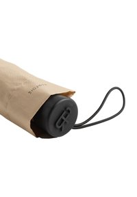 Czarny okrągły uchwyt parasola częściowo widoczny z beżowej osłony z tkaniny ze sznurkiem. Napis wytłoczony na uchwycie i osłonie z tkaniny.