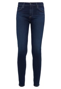 Jeans ajustados de mezclilla azul oscuro. Presentan una cintura de altura media, un diseño estándar de cinco bolsillos y detalles de costura sutil a lo largo de las costuras.