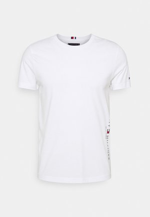 T-shirt bianca a maniche corte con scollo tondo, piccolo logo sulla manica sinistra e nome del marchio verticale con dettaglio della bandiera sul lato destro.