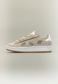 Bézs színű, velúrbőr sneaker három hímezett levélmintával, lapos fűzővel, gumitalppal és fehér sarokkal. Oldalán texturált díszítéssel.