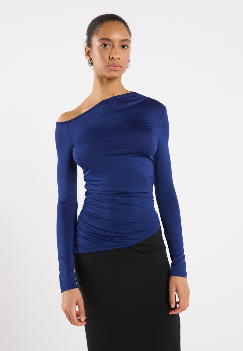 Navyblå långärmad topp med off-shoulder-design, med rynkade detaljer på sidan och ett mjukt, stretchigt tyg.
