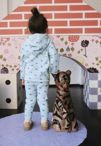 Light blue ribbed two-piece outfit with small floral patterns, featuring a hooded top and fitted pants. Accompanied by a brown striped dog statue.