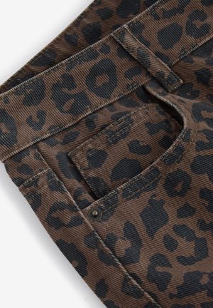 Tessuto a coste marrone con stampa leopardata, caratterizzato da macchie nere. Include una tasca posteriore con chiusura a bottone metallico e dettagli di cucitura visibili.