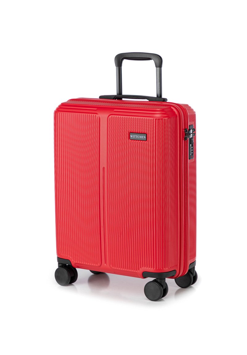 Valise rigide rouge avec une texture rainurée, poignée rétractable et quatre roues noires. Équipée d'un cadenas à combinaison sur le côté.