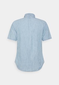 Ljusblå kortärmad skjorta i mjukt denimtyg, med klassisk krage och en något rundad nederkant.