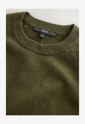 Pull en tricot de couleur vert olive, doté d'un col ras du cou et de poignets côtelés. Texture douce avec une étiquette affichant la marque 'NEXT' visible au niveau du col.
