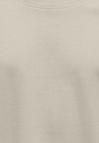 Camiseta de manga corta de color beige claro, hecha de una mezcla de algodón, con un escote redondo sencillo y textura suave sin ningún tipo de estampado.