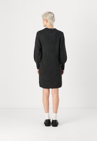 Robe en maille gris foncé avec de longues manches ballon, encolure ronde et longueur mi-cuisse. Présente une finition texturée et des poches latérales.