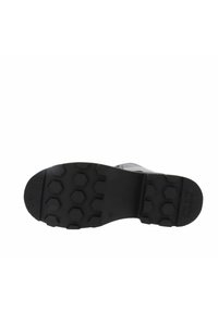 Sola di scarpa nera con motivi a nido d'ape e area del tallone texturizzata, che mostra il design della presa e il logo marka sul lato destro.