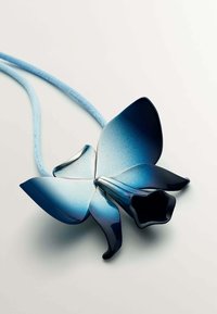 Colgante en forma de mariposa azul y negro con una superficie texturada y un cordón de color azul claro. Presenta diseños de pétalos detallados y un centro hueco.