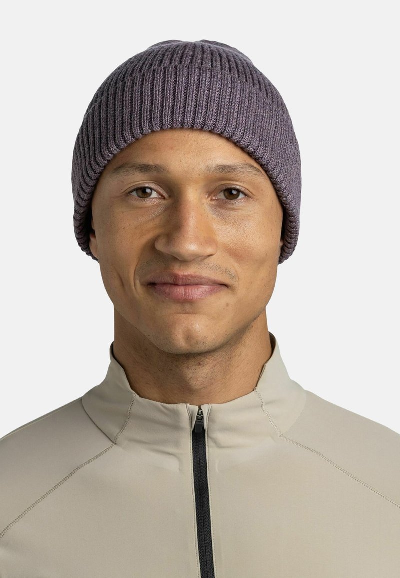 Knit beanie in muted lavender, featuring a ribbed texture and a snug fit, worn with a light beige zip-up jacket.