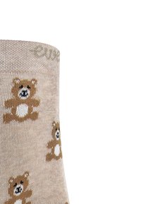 Beżowe skarpetki w brązowy i biały wzór z misiem. Miękka tekstura, ściągacz na górze i kreskówkowe twarze misiów w całym wzorze.