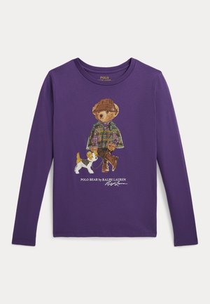 Chemise violette à manches longues avec un ours portant un chapeau et une veste à carreaux promenant un petit chien, légendé "Polo Bear by Ralph Lauren."