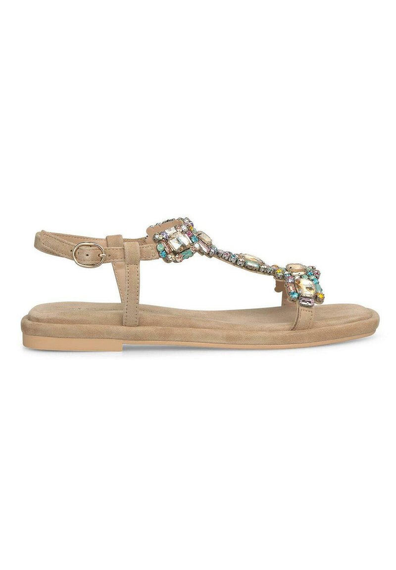 Sandales plates beiges avec un design à T, ornées de gemmes colorées. Elles présentent une surface texturée et une bride à la cheville réglable avec boucle.