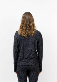 Schwarzes Langarm-Oberteil mit einem subtilen Leopardenmuster, aus weichem Stoff, kombiniert mit passenden Leggings, beide für Komfort designed.