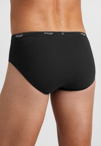 Brief in cotone nero con una texture liscia, design a vita bassa e una cintura morbida con il logo del brand stampato in bianco.