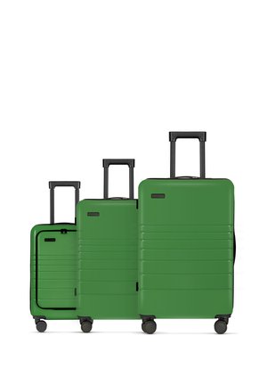 Three green hard-shell suitcases of varying sizes with smooth surfaces, black retractable handles, and four wheels each.