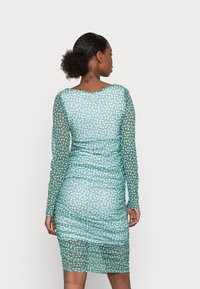 Vestido transparente em teal com mangas longas, design franzido, padrão floral branco, silhueta justa e decote redondo. Vista traseira mostrada.