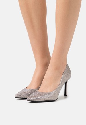 Silver högklackade pumps med spetsig tådesign, med en texturerad ovandel prydd med små dekorativa nitar. Svart stilettklack.